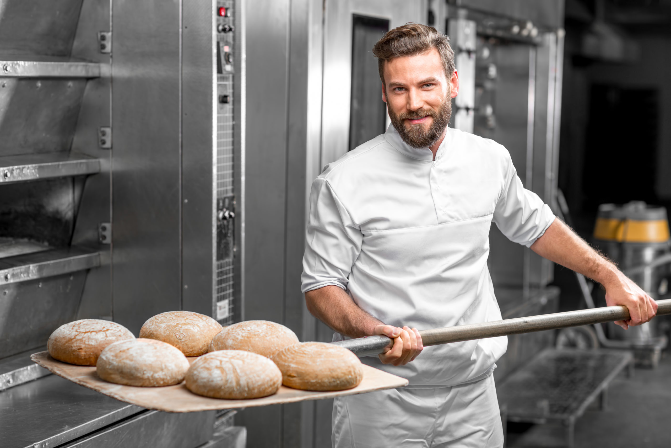 Bäcker mit Brot vor Ofen 