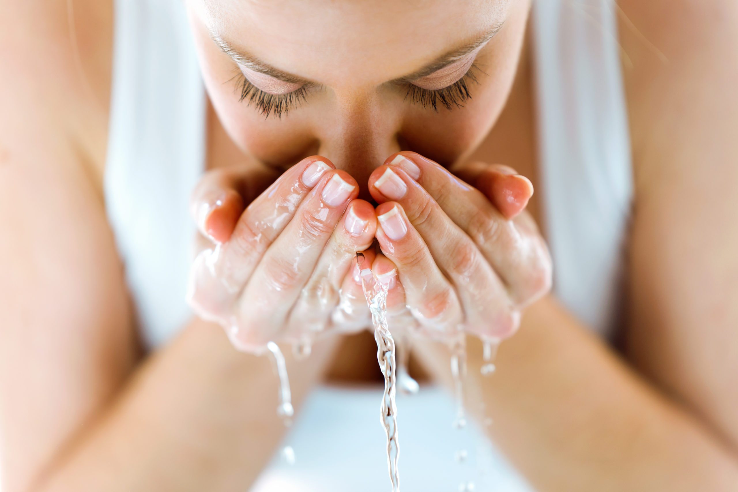 Portrait einer junge Frau, die ihr Gesicht mit Wasser im Badezimmer wäscht.