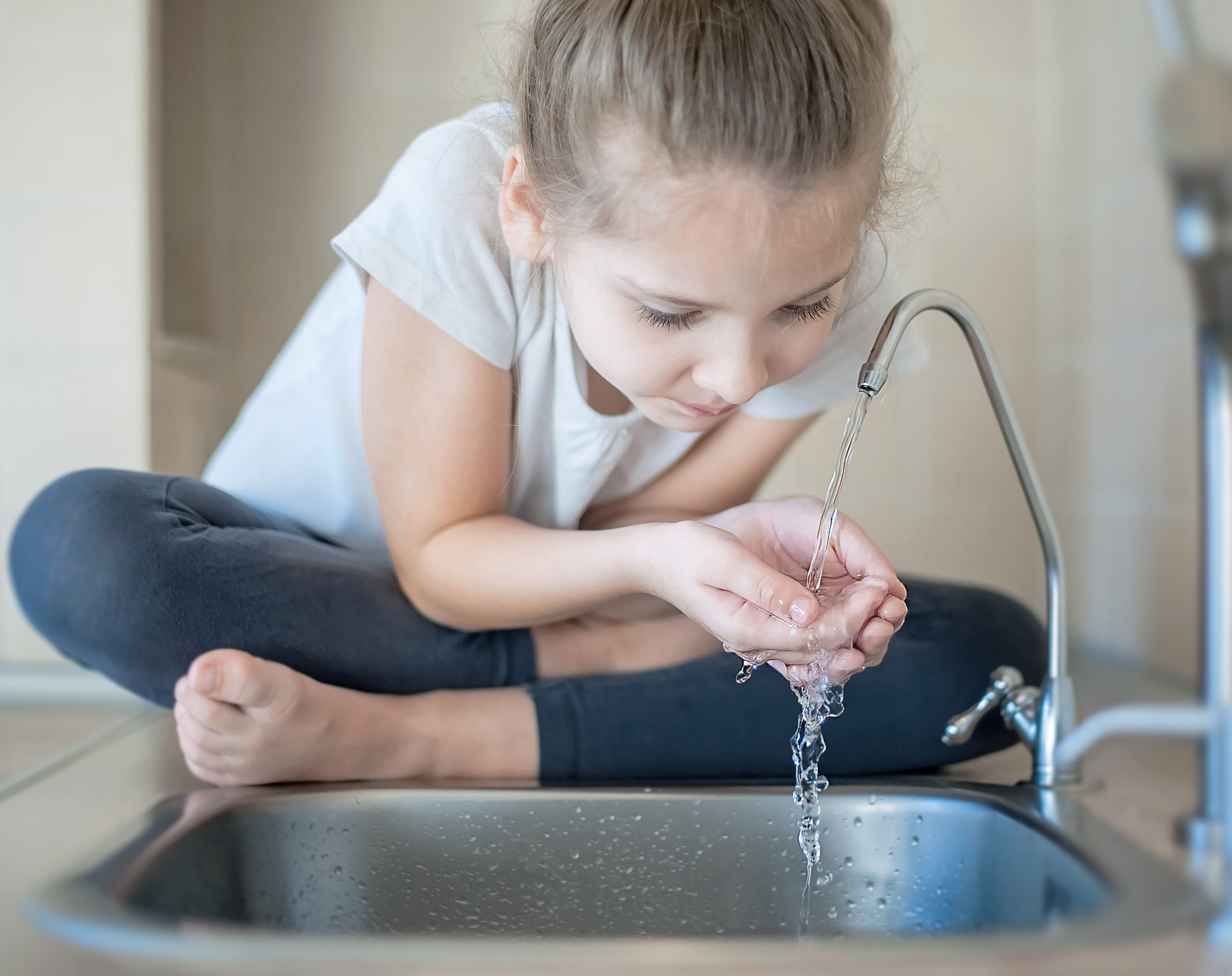 Mädchen Trinkt das Leitungswasser aus dem Wasserhahn