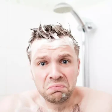 Mann in Dusche beim Haare waschen